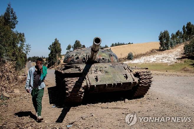 지난해 12월 내전으로 파괴된 탱크 옆을 걷는 에티오피아 젊은이. [AFP 연합뉴스 자료사진. 재판매 및 DB 금지]