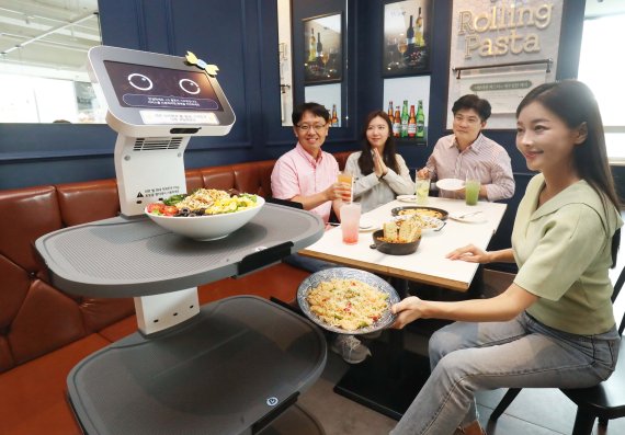 서울 구로구 롤링파스타 매장에서 LG 클로이 서브봇이 가져온 음식을 손님이 꺼내고 있다. LG유플러스 제공