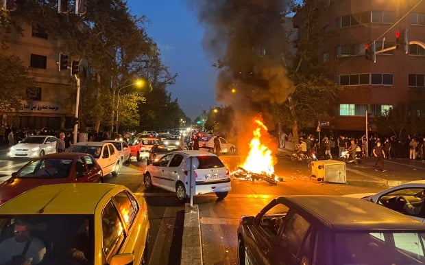 19일(현지시간) 이란 수도 테헤란 시내에서 '히잡 미착용 20대 여성 의문사 사건'에 항의하는 시위가 벌어진 가운데 경찰 오토바이가 불타고 있다. /사진=AP