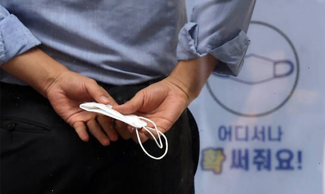지난 22일 서울 시내에서 한 시민이 마스크를 손에 들고 있다. 연합뉴스