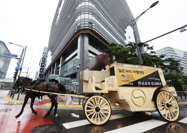 카카오게임즈의 '우마무스메:프리티 더비' 국내 이용자들이 게임사 측의 운영 방침에 반발하는 항의 문구 현수막을 붙인 마차가 지난달 29일 오전 카카오게임즈 본사가 위치한 경기도 성남시 판교역 인근 도로를 달리고 있다.연합뉴스