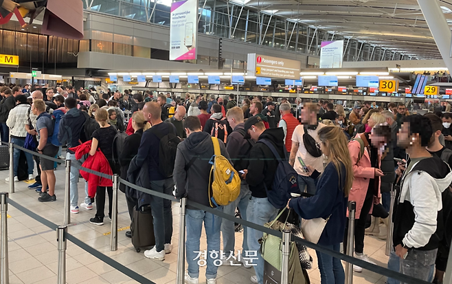 지난 19일 네덜란드 스키폴공항에서 이용객들이 체크인을 하기 위해 긴 줄을 서고 있다. 대부분은 실내에서도 마스크를 쓰지 않았다.