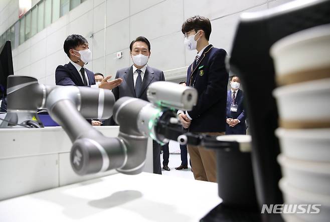 [광주=뉴시스] 전신 기자 = 윤석열 대통령이 28일 광주 서구 김대중컨벤션센터에서 열린 제8차 비상경제 민생회의에 앞서 AI TECH+ 박람회를 찾아 AI교육 선도학교 교육과정인 AI 솔루션 만들기 실습 중 학생들이 개발한 로봇 팔 활용 배지·커피 제작 시연을 지켜보고 있다. 2022.09.28. photo1006@newsis.com