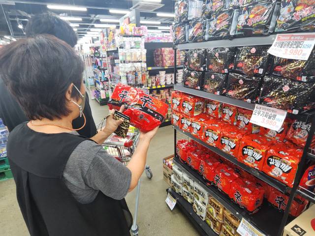 ▲ 마트에서 라면 가격과 열량 등을 확인하고 있는 소비자 모습.