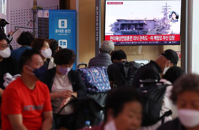 Passersby watch a TV report of North Korea’s missile launch at Seoul Station on Sunday. (File Photo - Yonhap)