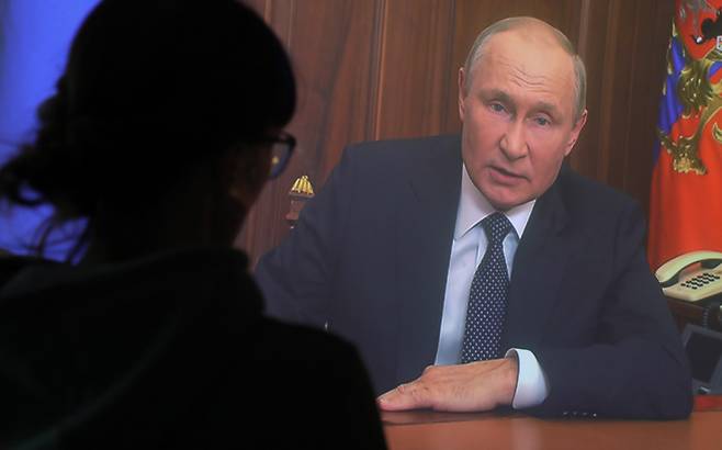 지난 21일(현지시간) 러시아 수도 모스크바에서 한 여성이 블라디미르 푸틴 러시아 대통령의 대국민 연설을 TV 화면으로 지켜보고 있다. [연합]