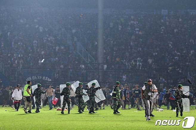 1일(현지시간) 인도네시아 동부 자바 말랑 리젠시의 칸주루한 구장에서 '아르마 FC'와 '페르세바야 수라바야' 축구팀의 경기가 끝난 후 경찰이 그라운드로 난입한 관중들을 진압하고 있다.  ⓒ AFP=뉴스1 ⓒ News1 박정호 기자