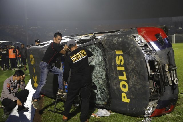 경찰 관계자들이 두 인도네시아 축구팀 지지자들 간의 충돌로 파손된 경찰차를 조사하고 있다. AP 뉴시스