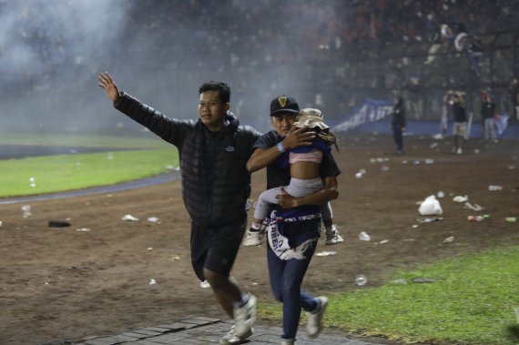 1일 인도네시아 이스트 자바 말랑의 칸주루한 스타디움에서 축구 팬들끼리 충돌하면서 130여명이 숨지는 참사가 발생했다. 가족으로 보이는 사람들이 한 소녀를 대피시키고 있다. /EPA 뉴시스