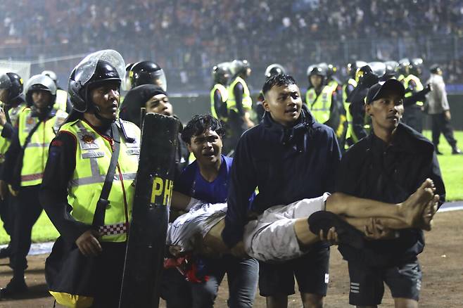 1일 폭동이 발생한 인도네시아 자바의 칸주르한 경기장에서 축구팬들이 부상자를 옮기고 있다. 자바/AP 연합뉴스