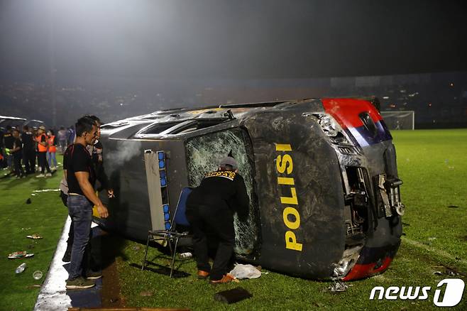1일(현지시간) 인도네시아 동부 자바 말랑 리젠시의 칸주루한 구장에서 '아르마 FC'와 '페르세바야 수라바야' 축구팀의 경기가 끝난 후 관중들이 파손된 경찰차 옆에 서 있다.  /사진=뉴스1