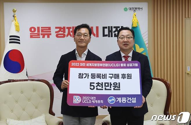 이승찬 계룡건설 사장(왼쪽)이 이장우 대전시장(오른쪽)에게 2022 대전 세계지방정부연합(UCLG) 총회 참가 등록비 후원금을 전달한 후 기념사진을 찍고 있다.(계룡건설 제공)