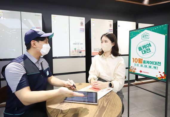 롯데하이마트 대치점에서 홈케어 CS마스터가 매장에 방문한 소비자에게 ‘홈케어 대전’ 행사를 소개하고 있다.