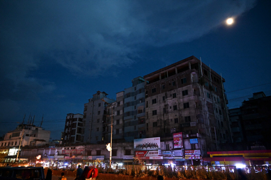 5일 밤 방글라데시의 수도 다카의 주요 도로에 일부 상점들이 불을 켜고 있다. 이날 발생한 전력망 고장 사태로 전체 인구의 80%가 정전을 겪었다.  AFP·연합뉴스