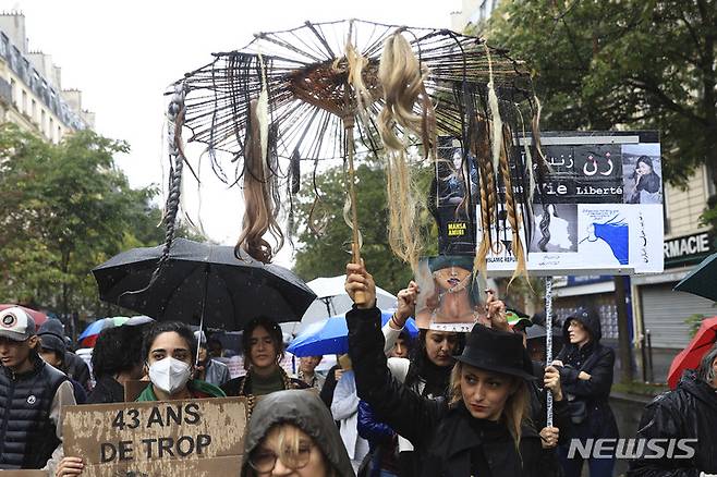 [파리=AP/뉴시스] 시위자가 2일(현지시간) 프랑스 파리에서 이란 경찰에 구금되던 중 사망한 젊은 여성을 추모하는 시위대에 연대하기 위해 가짜 머리카락이 달린 우산을 들고있다. 2022.10.06.