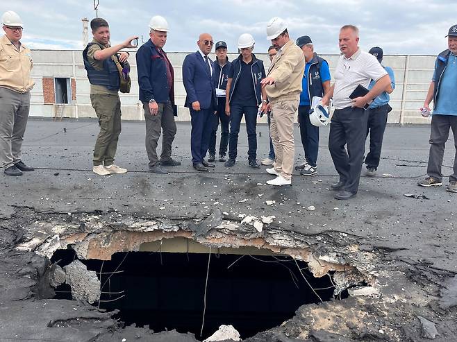 국제원자력기구(IAEA)의 라파엘 그로시(가운데) 사무총장과 사찰단이 지난 1일(현지시간) 우크라이나 자포리자 원자력발전소를 방문해 포격으로 손상된 건물 지붕을 살펴보고 있다. /AFP 연합뉴스