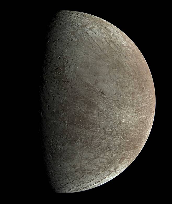 목성의 위성 유로파의 표면. 왼쪽은 밤인 곳이고 오른쪽 밝은 곳은 낮이다. 시민과학자가 주노 탐사선이 근접 촬영한 원본의 해상도를 높여 표면의 상세한 모습까지 확인할 수 있다./NASA/Björn Jónsson 가공