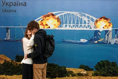 8일(현지시간) 우크라이나 키이우에서 크림대교가 폭발하는 장면을 형상화한 대형 시각물 앞에서 남녀가 키스하고 있다. 로이터 연합뉴스
