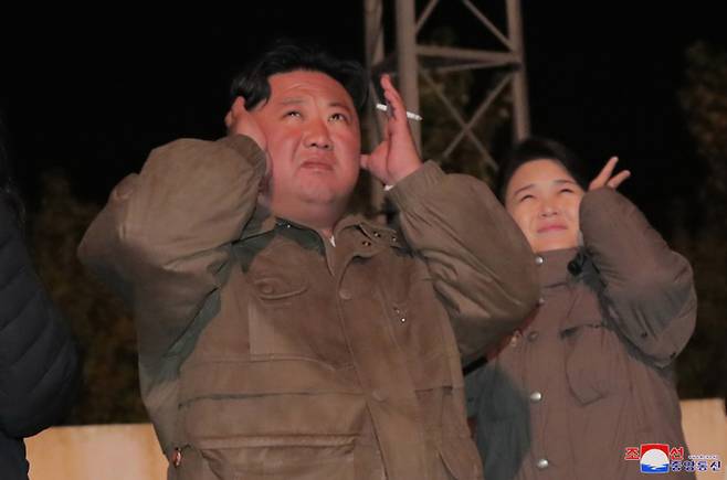 North Korean leader Kim Jong-un (left) covers his ears with his wife Ri Sol-ju during an inspection of major drills in this photo provided by the North's Korean Central News Agency on Monday. (Yonhap)