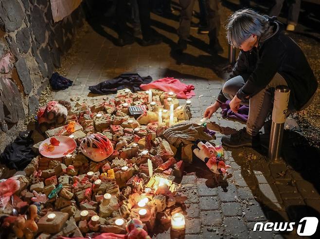 17일(현지시간) 우크라이나 키이우의 이란 대사관 앞에서 한 활동가가 러시아 드론 공습으로 사망한 사람들을 기리기 위해 촛불을 켜고 있다. 이날 키이우를 공격하는 데 사용된 무인항공기(UAV) 샤헤드-136은 이란제로 알려졌다. ⓒ 로이터=뉴스1 ⓒ News1 권진영 기자