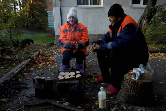 우크라이나가 최근 재탈환한 하르키우 주의 쿠피안스크 지역에서 지난 15일(현지시간) 주민들이 군이 제공한 빵을 군불에 데우며 식사를 준비하고 있다. 로이터·연합뉴스