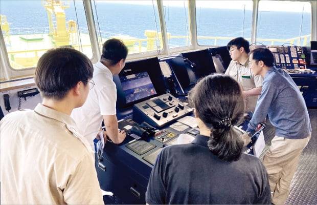 현대중공업그룹 계열 자율운항기술 전문업체인 아비커스와 SK해운 직원들이 세계 최초로 ‘자율운항 대양횡단’에 성공한 LNG 운반선 ‘프리즘 커리지’호 조타실에서 AI 운항 기기를 점검하고 있다. 현대중공업 제공