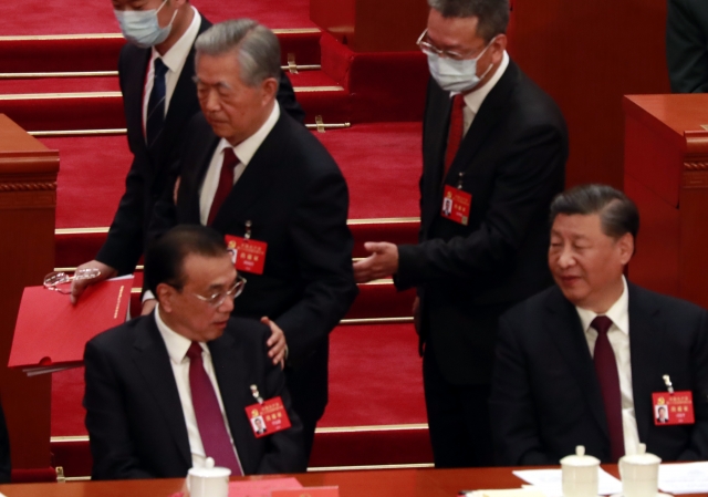 후진타오(앞줄 왼쪽 뒤) 전 중국 주석이 지난 22일 수도 베이징 인민대회당에서 열린 제20차 공산당 전국대표대회 폐막식 도중 자리를 떠나면서 리커창(앞줄 왼쪽) 총리의 어깨를 다독이고 있다. 그 옆에서 시진핑(앞줄 오른쪽) 주석이 리 총리 쪽을 바라보고 있다. 연합뉴스