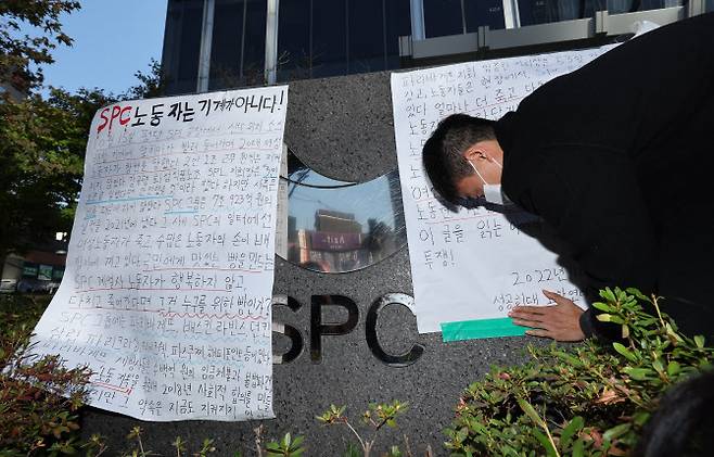 20일 오후 서울 양재동 SPC 본사 앞에서 열린 평택 SPC 계열사 SPL의 제빵공장 사망 사고 희생자 서울 추모행사에서 성공회대 노학연대모임 가시 관계자가 대자보를 붙이고 있다. (사진=연합뉴스)
