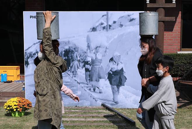 23일 오전 부산 서구 임시수도기념관에서 피란학교 천막교실 체험학습 프로그램에 참가한 학생과 학부모들이 물동이를 이고 걷고 있다. /2022.10.23 김동환 기자