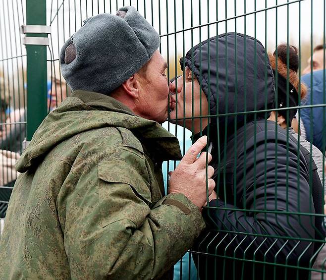 러軍 동원령 받고… 철조망 사이로 작별 - 23일(현지 시각) 러시아 수도 모스크바에서 동쪽으로 800㎞ 떨어진 도시 카잔에서 군 동원령을 받고 참전하게 된 한 남성이 파병 전 환송 행사에서 철조망을 사이에 두고 애인과 입을 맞추고 있다. 지난달 21일 블라디미르 푸틴 러시아 대통령이 예비군 30만명 동원령을 선포한 이후 수십만 명의 러시아 남성이 키프로스 등 외국으로 피신한 것으로 알려졌다. /타스 연합뉴스