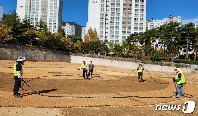 25일  부산 기장군 정관읍 모전리 공사현장에서 관계자들이 산책로 구간에 유채씨 파종을 마치고 살수차 호스를 이용해 물을 공급하고 있다.2022.10.25(기장군청 제공)