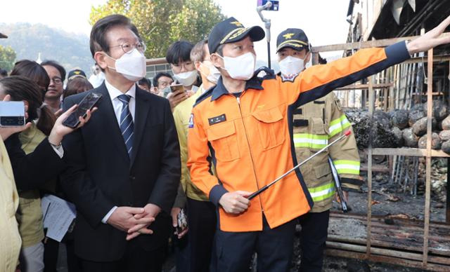 이재명 더불어민주당 대표가 28일 대구 북구 매천동 농수산물 도매시장 화재 현장을 방문해 소방 관계자에게 설명을 듣고 있다. 연합뉴스.