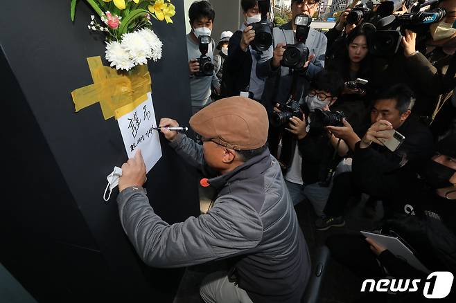 30일 오후 서울 용산구 이태원 압사 사고 현장 인근에서 한 시민이 추모를 위해 꽃을 붙이고 있다. 2022.10.30/뉴스1 ⓒ News1 임세영 기자