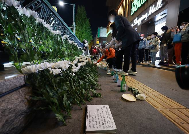 People lay flowers near the accident scene in Seoul’s Itaewon district, Sunday. (Yonhap)