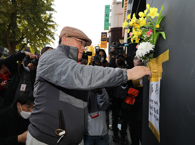 30일 오후 서울 용산구 이태원 핼러윈 참사 현장 인근 건물 외벽에 한 시민이 조화를 붙이며 희생자들을 애도하고 있다. 뉴시스