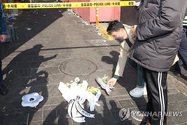 사고 추모하는 시민 (서울=연합뉴스) 신현우 기자 =  30일 오후 서울 용산구 이태원동 '핼러윈 인파' 압사 사고 현장을 찾은 시민이 꽃을 놓고 있다. 2022.10.30 nowwego@yna.co.kr