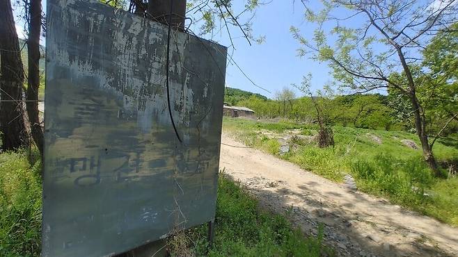 지난 5월6일 오전 11시께 찾은 인천 계양구 계양산에 있는 아크보호소(옛 계양산보호소) 들머리 모습. “맹견 있슴”이 적혀 있던 표지판 뒤로 개 보호소로 사용 중인 건물이 보인다.