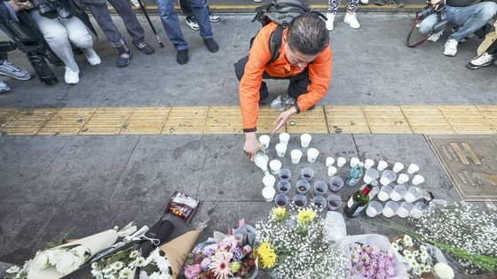이태원 참사 희생자를 추모하는 한 시이 30일 참사 현장 인근인 서울 용산구 이태원역 1번 출구 해밀튼호텔 앞에 놓인 조화 앞에 술을 따르고 있다. 김성룡 기자