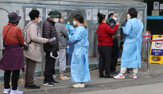 People stand in line to get tested for Covid-19 at a testing center in Busan on Sunday. [JOONGANG ILBO]