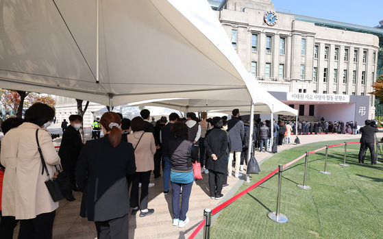 People wait in line to pay their respects to victims of the Halloween tragedy in Itaewon at a mourning altar set up on Seoul Plaza on Monday.  [YONHAP]