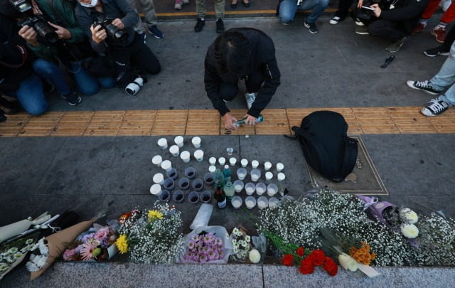 30일 오후 서울 용산구 지하철 6호선 이태원역 1번 출구 앞에 마련된 '핼러윈 인파' 압사 사고 희생자 추모 공간에서 한 시민이 술을 올리고 있다. 연합뉴스