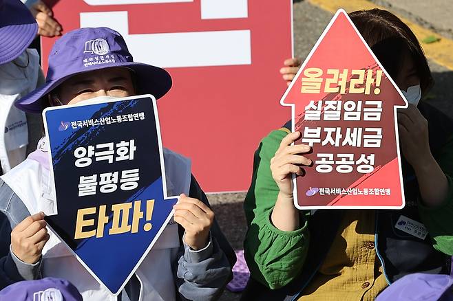 전국서비스산업노동조합연맹 조합원들이 11일 오후 서울 용산구 대통령 집무실 인근에서 열린 민생대회에서 팻말을 들고 있다. [연합]