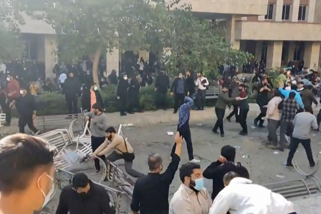 ▲30일(현지시각) 이란 수도 테헤란의 한 대학에서 일어난 반정부 시위 도중 사복 경찰로 추정되는 인물(왼쪽)이 시위대 사이에서 발포하고 있다. ⓒAFP=연합뉴스