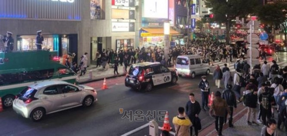 지난달 31일 핼러윈축제가 벌어진 일본 도쿄 시부야 번화가 모습. 경찰(왼쪽)이 개조 차량 위에 올라가 확성기를 통해 인파를 분산시키고 있다.도쿄 김진아 특파원