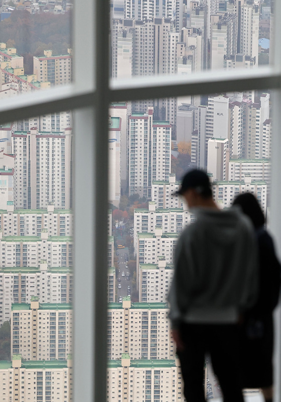 People look down at apartment complexes in downtown Seoul from the Lotte World Tower in Songpa District, western Seoul, on Thursday. As the housing market stagnates due to interest rate hikes and a sharp decrease in transactions, the range of declines in sales prices and jeonse prices is widening. This week, apartment sales prices in Seoul fell again recording 23 consecutive weeks of price declines, and the nationwide apartment sales and jeonse prices in the metropolitan and regional areas recorded the steepest decline in history since May 2012 when the Korea Real Estate Board started collecting related data. [YONHAP]