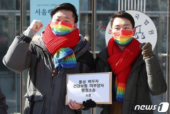 결혼 5년차 동성 부부 소성욱(왼쪽), 김용민 씨가 18일 오전 서울 서초구 양재동 서울행정법원 앞에서 가진 동성 배우자 건강보험 피부양자 소송 기자회견에서 소장을 함께 들고 구호를 외치는 포즈를 취하고 있다. 2021.2.18/뉴스1 ⓒ News1 박정호 기자