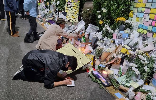 5일 밤 11시쯤 서울 용산구 이태원역 1번 출구 근처에 마련된 핼러윈 압사 참사 추모 공간에 한 남성이 바닥에 엎드려 종이에 글을 적고 있다. /김명진 기자
