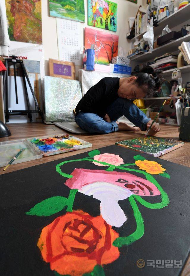 족필화가 이윤정 작가가 지난달 22일 서울 노원구 작업실에서 손대신 발로 붓을 놀리고 있다.