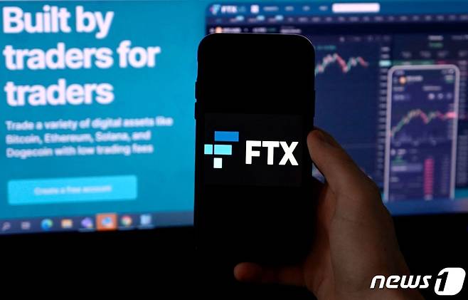 한 사람이 FTX 웹사이트와 FTX 애플리케이션 화면을 보여주고 있다. ⓒ AFP=뉴스1 ⓒ News1 김지현 기자