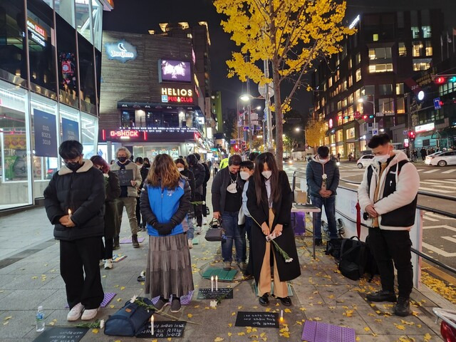 15일 저녁 서울 지하철 이태원역 2번 출구 인근에서 열린 ‘이태원 참사를 추모하는 이들의 오픈마이크’ 집회에서 참가자들이 희생자들을 위한 묵념을 하고 있다. 고병찬 기자